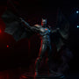 Black fabric cape wings with wire edges on armored Batman figure in Batcave diorama with red and blue lighting and fog.