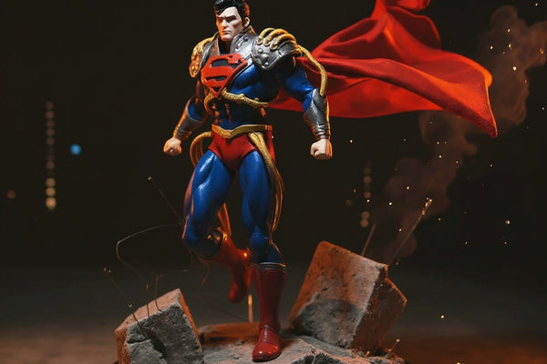 Handmade deep red cloth cape with gold trim on a McFarlane action figure, posed dramatically on a cracked concrete diorama with city skyline backdrop and red/yellow gel lighting.