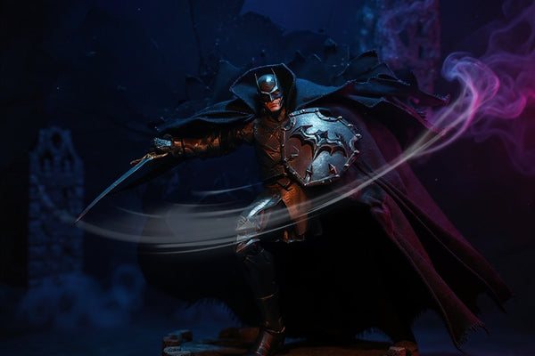 Medieval-armored Batman figure with a dark charcoal matte fabric cape, posed on stone ruins with gothic backdrop and dramatic purple lighting.