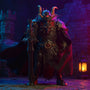 Dark textured cloak on a 9-inch figure against a stone castle and lantern, bold gradient background.