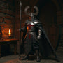 Flowing fabric action figure cape on knight figure with medieval castle backdrop and candle-lit props, showcasing wire-shaped drape and woven texture.