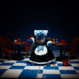Miniature maid costume on an articulated figure in a café diorama with tea set, bold blue and white background, dramatic lighting.