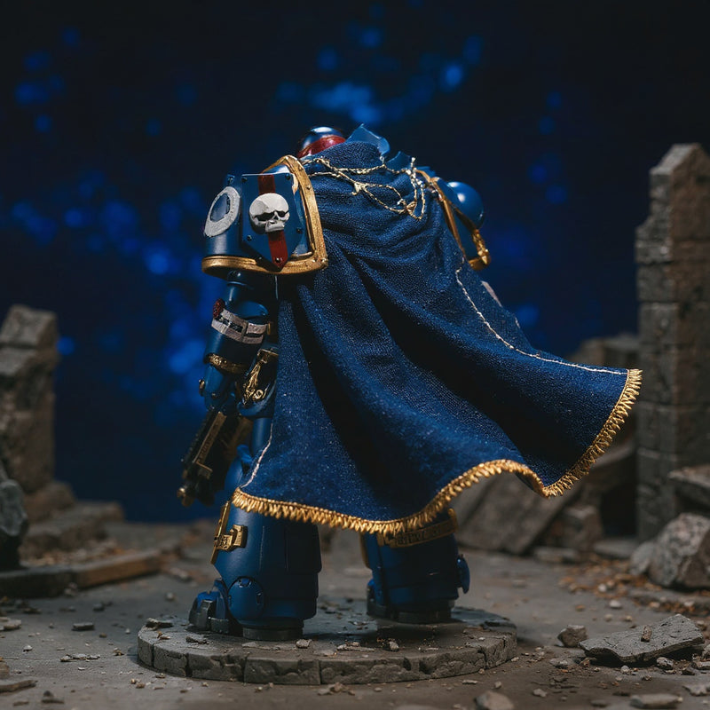 Deep blue fabric cape with gold trim and purity seal draped over a 1/18 action figure shoulder in a miniature battlefield diorama with dramatic spotlighting.