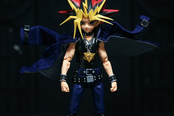 Yami Yugi action figure with wired fabric cloak posed heroically on a dark diorama with scattered dueling cards.