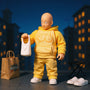 Soft fabric yellow 1/12 scale jumpsuit on bald superhero action figure in urban rooftop diorama with grocery bags, slippers, and stool.