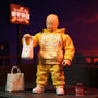 Hero shot of a 1/12 scale soft fabric yellow jumpsuit with white accents on a bald superhero action figure, posed on an urban rooftop diorama with grocery bags and noodle cup, under dramatic neon lighting.