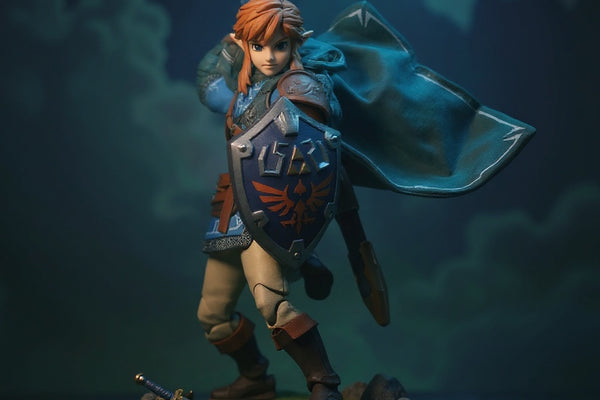 Hero image of a Zelda TotK soft goods cloak in blue-green fabric, dynamically posed with wire-shaped folds, draped over an armor torso on a Hyrule-themed diorama base with rocks, moss, and Master Sword, under dramatic blue-hour lighting.
