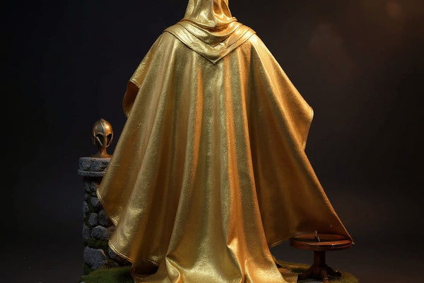 Golden wire-edged cape draped over invisible form on fantasy stone castle diorama with helmet and sword, dramatic blue-gold gradient background.