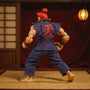 Tattered dark red and grey karate gi on a small action figure in mid-kick under moody dojo lighting with tatami and lantern.