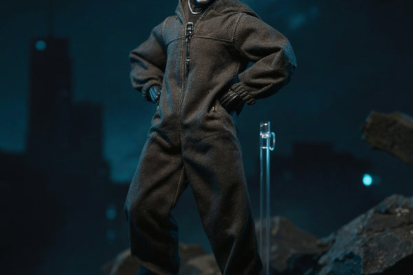 Dark tactical protective suit on a headless 1/12 scale action figure body, displayed on miniature urban rubble diorama with LED glow and rooftop backdrop.