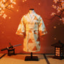 Pale yellow haori cloak with orange triangles on headless action figure torso, cherry blossom and Japanese lantern background