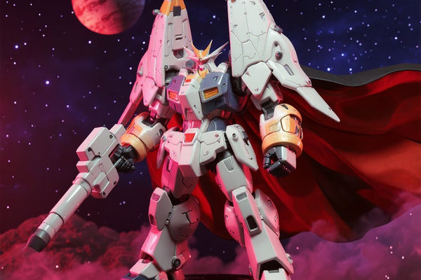 White and blue Gunbuster action figure with red poseable cape and weapon, standing on round base against starry space backdrop with distant planet and smoke effects.