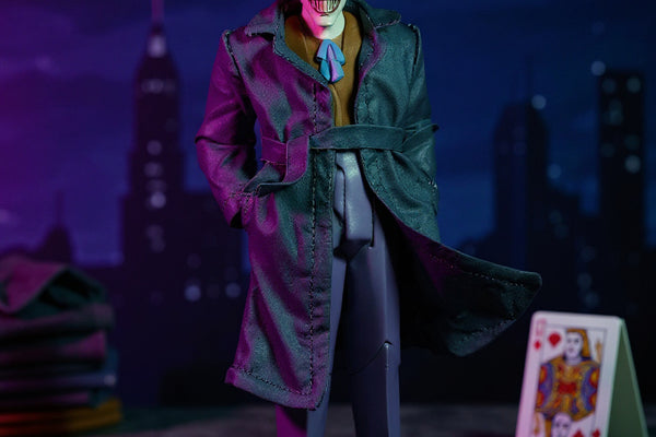 Dark grey or purple fabric trench coat for 7-inch action figure flat-laid on miniature Gotham rooftop with playing card and fabric swatches, dramatic purple and green lighting.