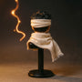 Cream soft goods scarf with visible wire draped over a miniature action figure neck stand, against a bold gradient backdrop with Hamon energy light effects.