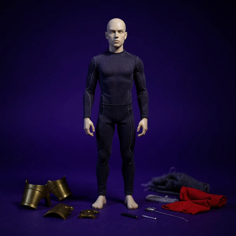 Small dark fabric body suit with wire framework fitted on a miniature figure frame, surrounded by bronze armor pieces and sewing kit on a bold blue-violet gradient background.